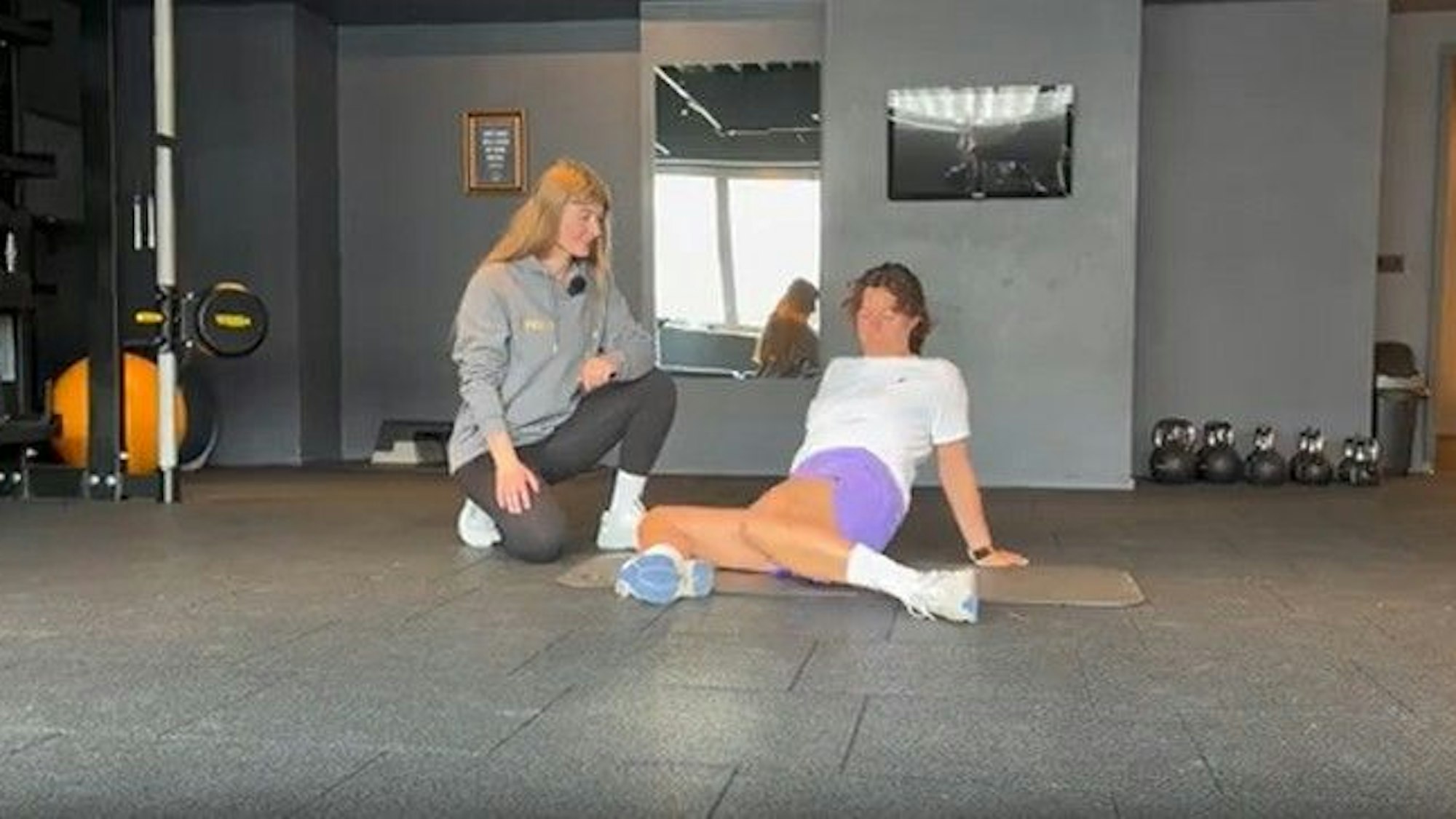 Eine Fitnesstrainerin erklärt einer Frau eine Sportübung.