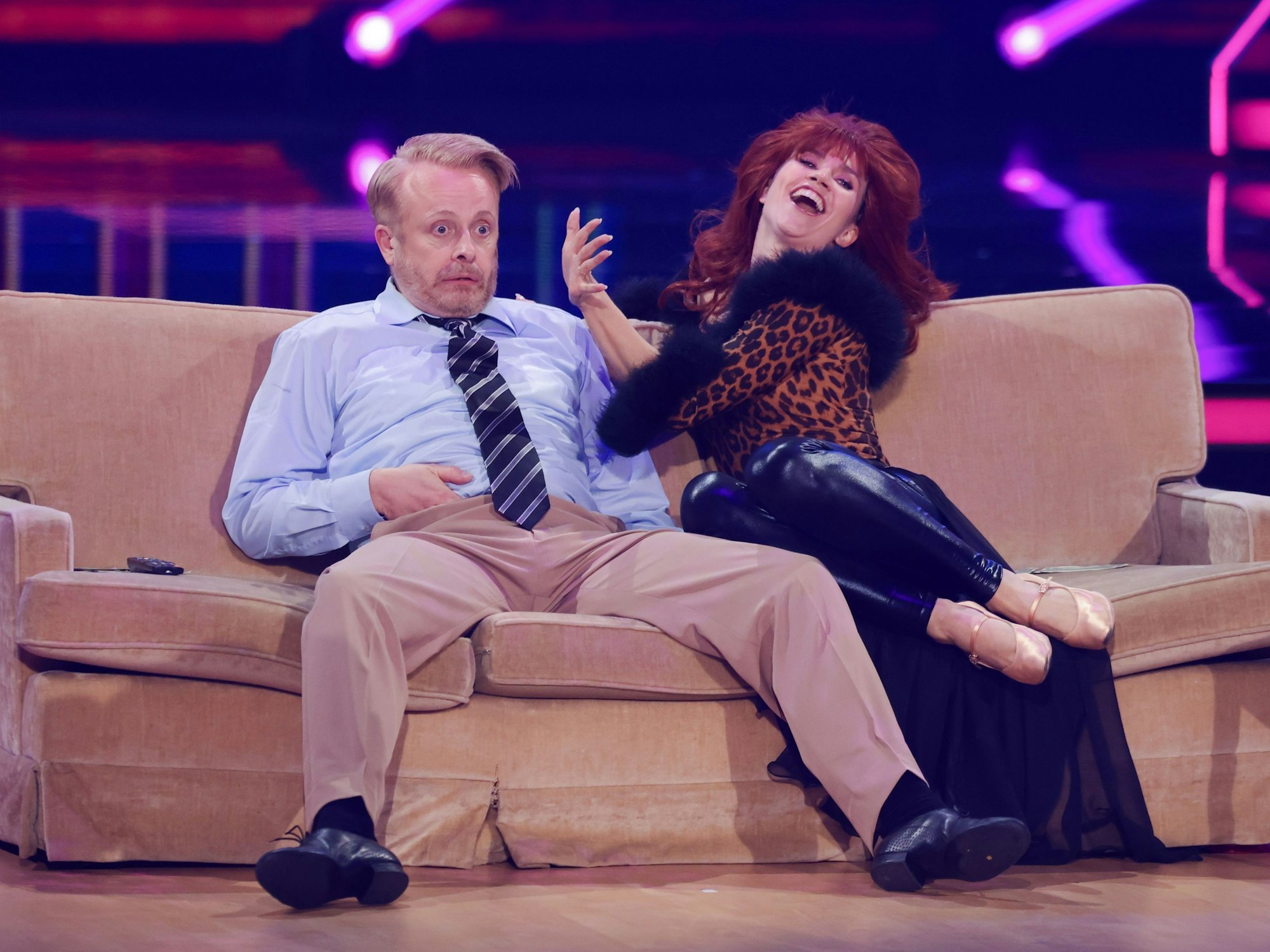 Ross Antony und Mariia Maksina sitzen auf dem Sofa.