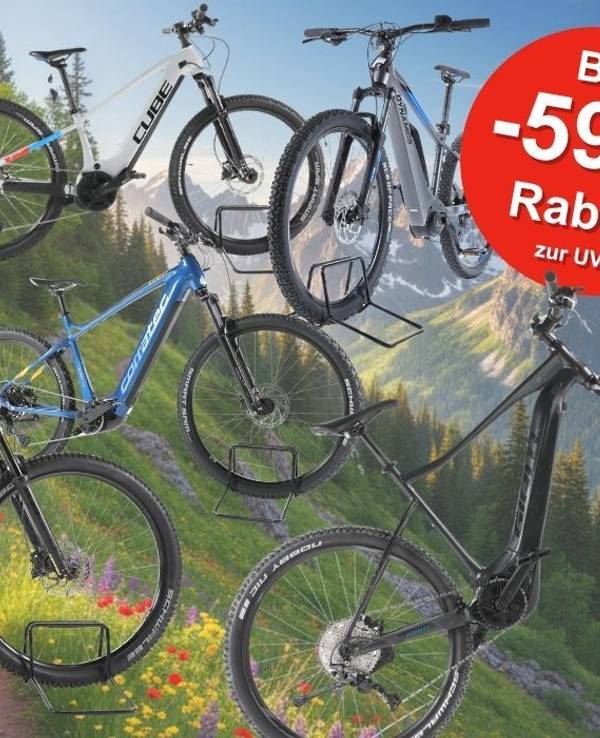 Fünf E-Mountainbikes der Marken Cube, Corratec, KTM und mehr in verschiedenen Farben (hellblau, weiß-schwarz, rot, blau, schwarz), präsentiert vor einer alpinen Berglandschaft mit Blumenwiese. Ein roter Kreis-Badge oben rechts zeigt „Bis -59 % Rabatt zur UVP". Logo von REBIKE oben links.