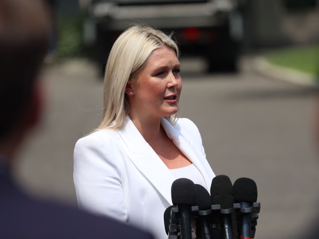 Karoline Leavitt steht auf einer Straße und spricht in mehrere Mikrofone.