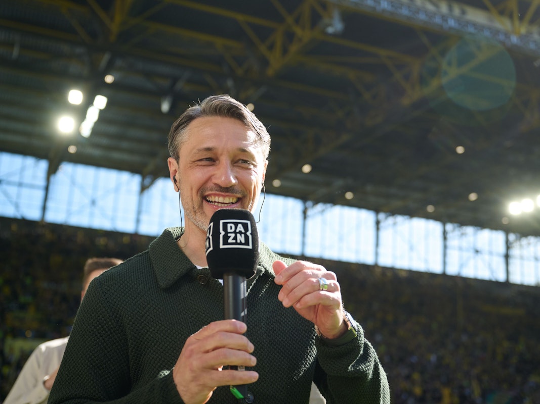 Nico Kovac lacht und hat ein DAZN-Mikrofon in der Hand.