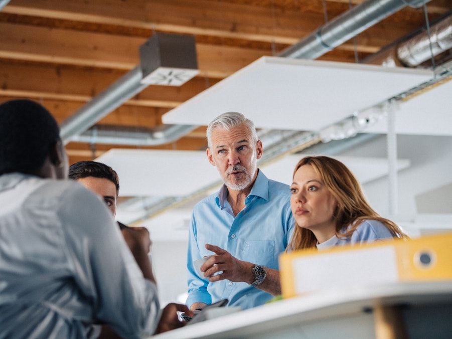 Eine Gruppe Kolleginnen und Kollegen an einem Stehtisch