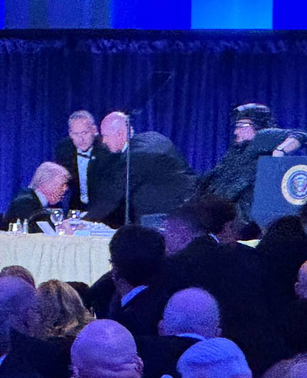 US-Präsident Donald Trump (l) sitzt auf der Bühne, während Agenten des US-Geheimdienstes ihn nach einem Vorfall außerhalb des Ballsaals während des White House Correspondents' Dinner aus dem Ballsaal bringen.