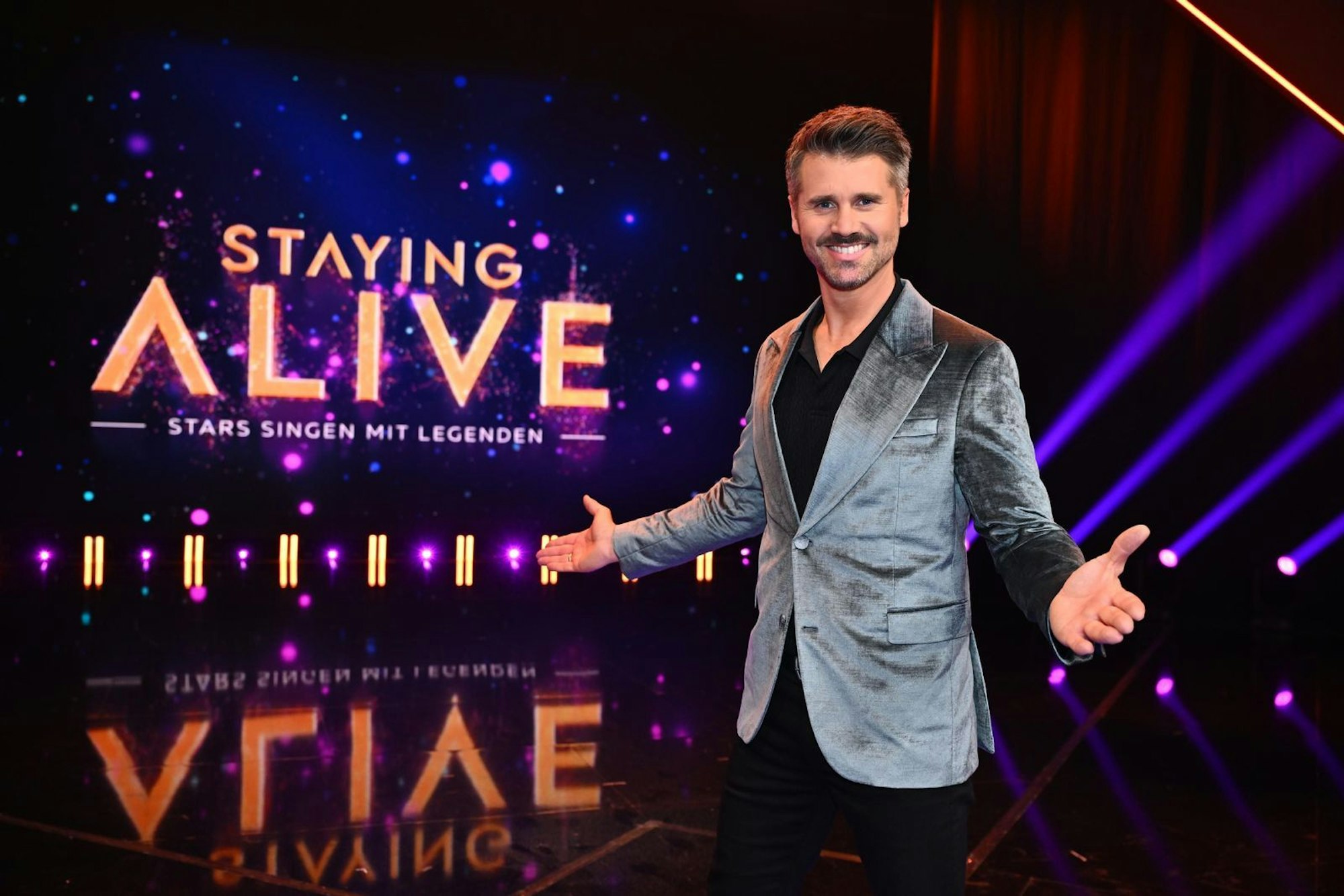 Moderator Thore Schölermann fragt den Fake-Elvis, ob dieser an Lampenfieber leide. (Bild: Joyn / Julia Feldhagen)