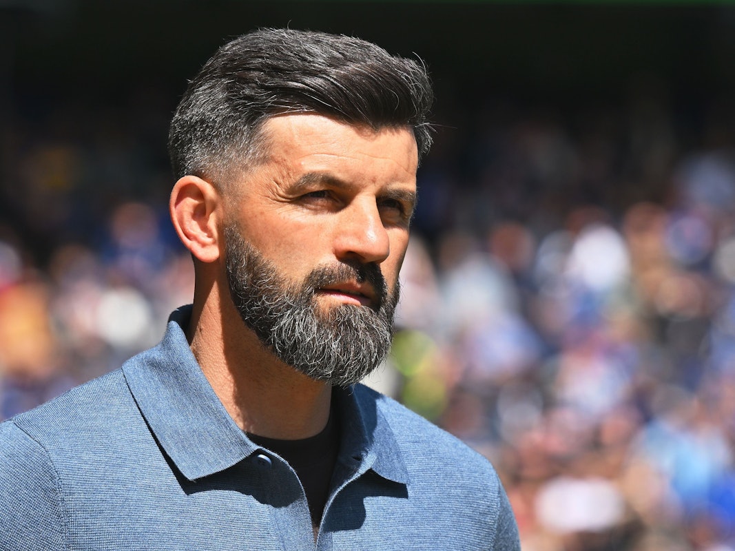 Trainer Miron Muslic steht am Spielfeldrand in der Sonne.