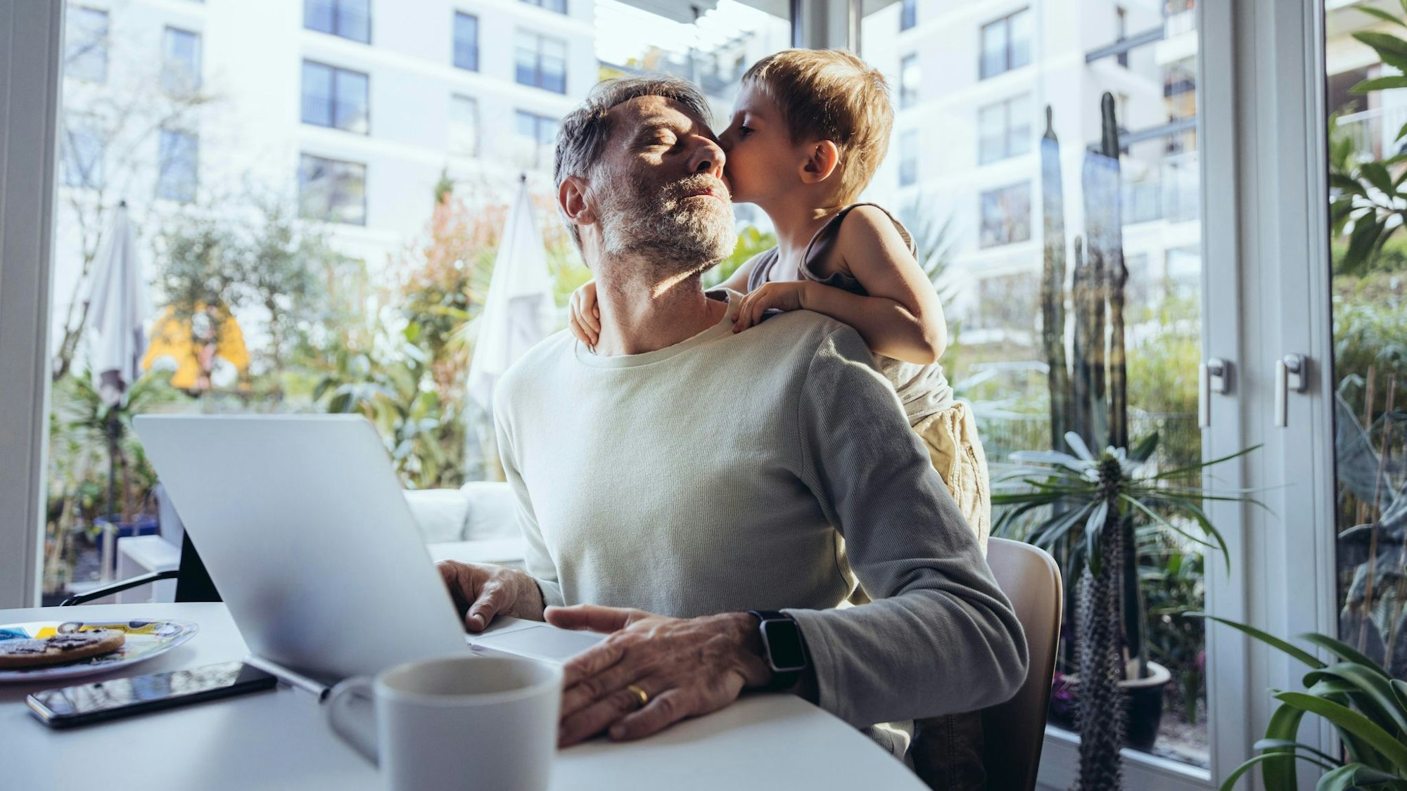 Mann mit Sohn arbeitet im Homeoffice