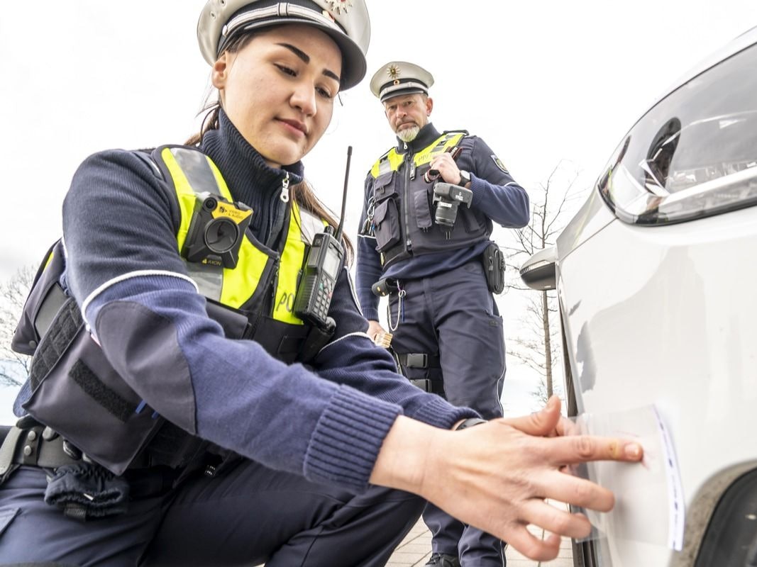 Ein Polizeiauto steht mit Blaulicht an einer Straße.