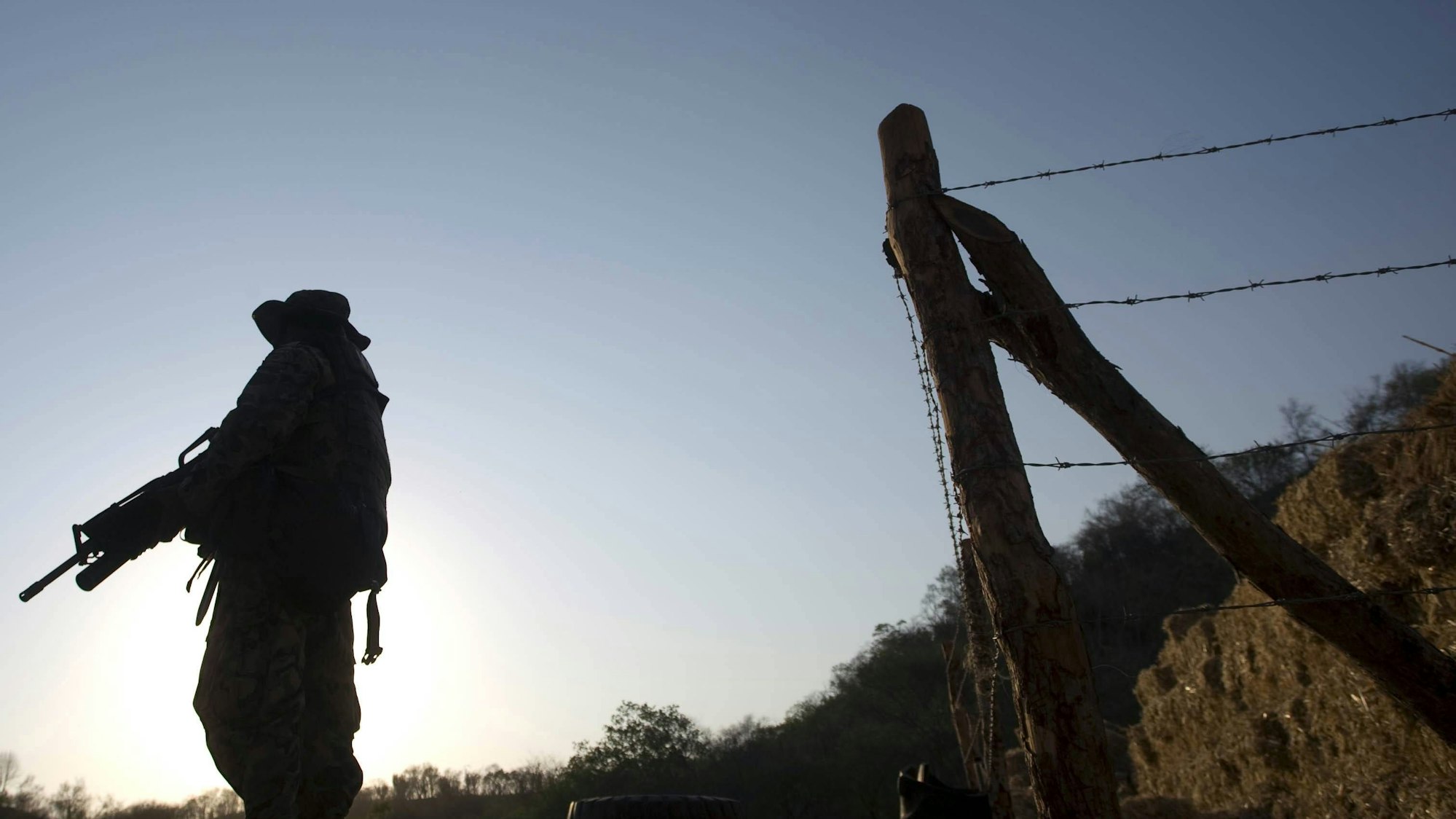 Soldat mit Gewehr und Stacheldrahtzaun