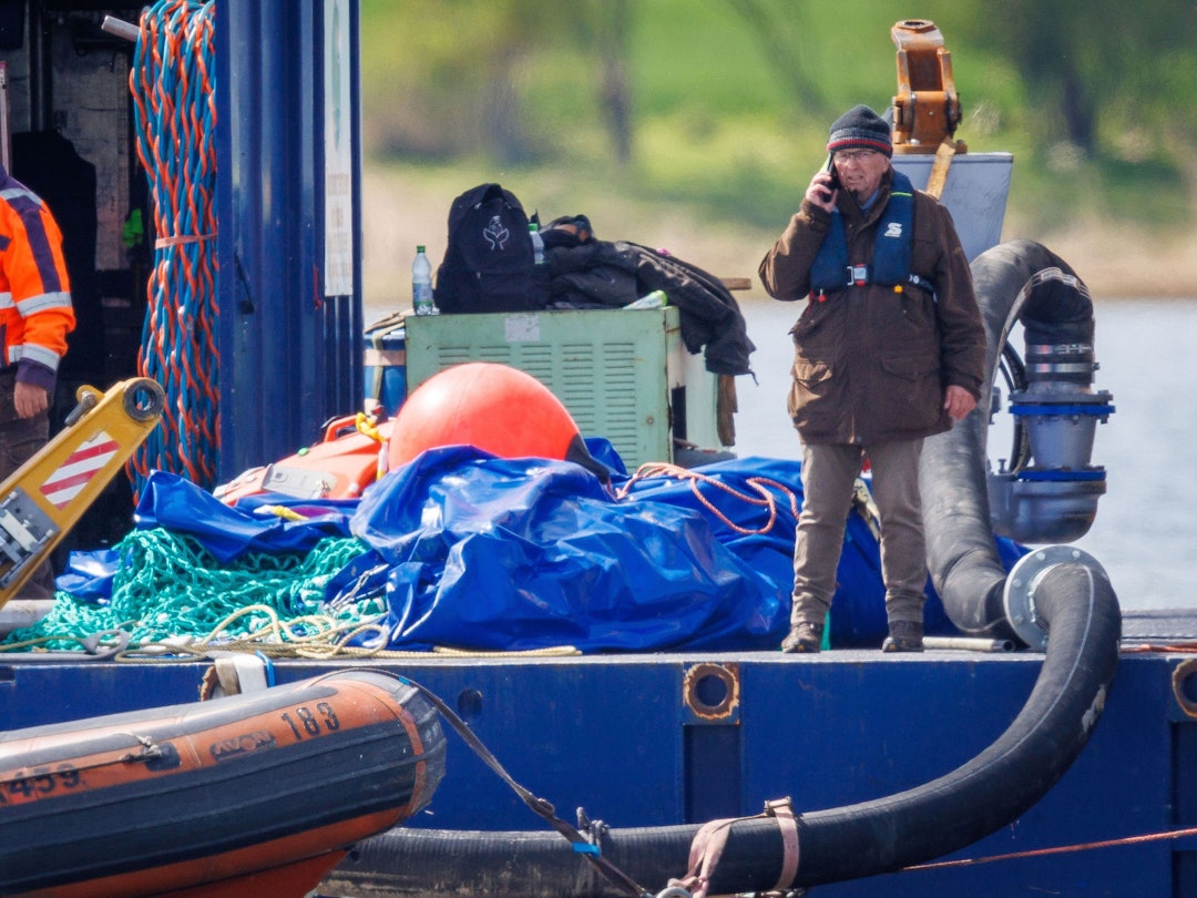 Till Backhaus (r, SPD), Umweltminister von Mecklenburg-Vorpommern, telefoniert, nachdem der gestrandete Buckelwal vor der Insel Poel mit Gurten in den Lastkahn gezogen wurde.