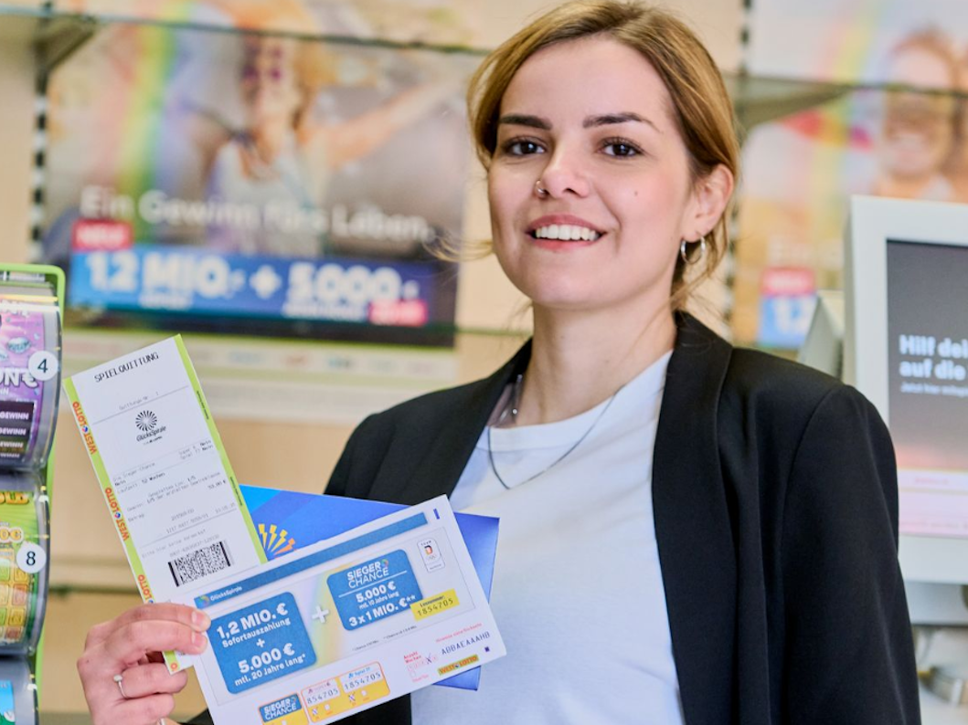 Eine Frau in einer WestLotto-Annahmestelle, die eine Spielquittung für ein Los der GlücksSpirale in der Hand hält.
