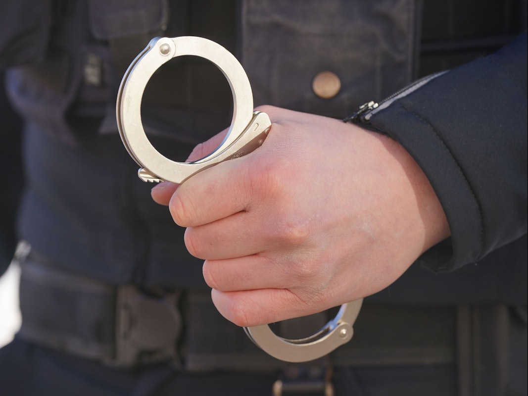 Ein Polizist hält Handschellen in der Hand.