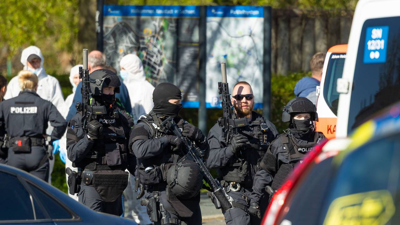 Polizisten und Mitarbeiter der Spurensicherung stehen in der Nähe des Tatortes. Nach Schüssen im Bereich eines Mehrfamilienhauses hat die Polizei zwei Tote und einen Schwerverletzten entdeckt. Die Hintergründe der Tat sind noch unklar.