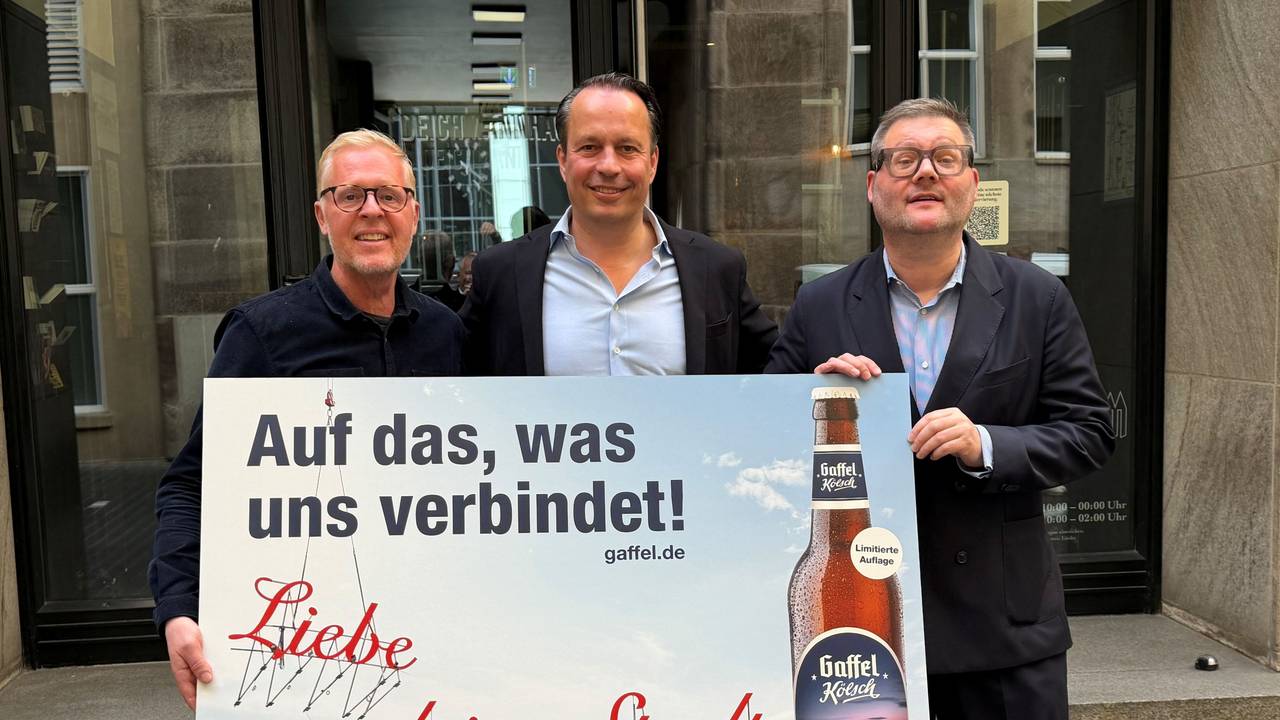 Thomas Deloy, Heinrich Philipp Becker und Künstler Merlin Bauer zeigen ein Poster.