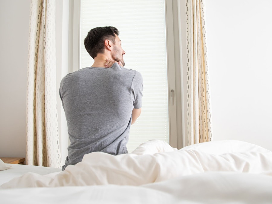 Ein Mann hält sich seine verspannten Muskeln am Nacken