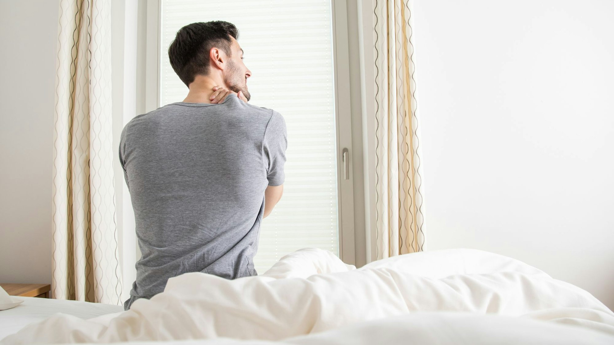 Ein Mann hält sich seine verspannten Muskeln am Nacken
