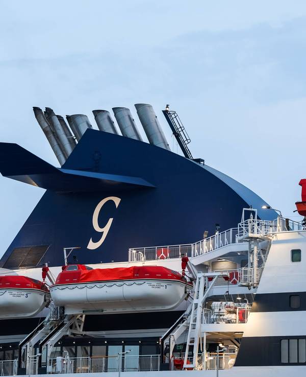 Schornstein eines Fährschiffs mit einem G-Logo und mehreren Rettungsbooten zur Sicherheit der Passagiere.