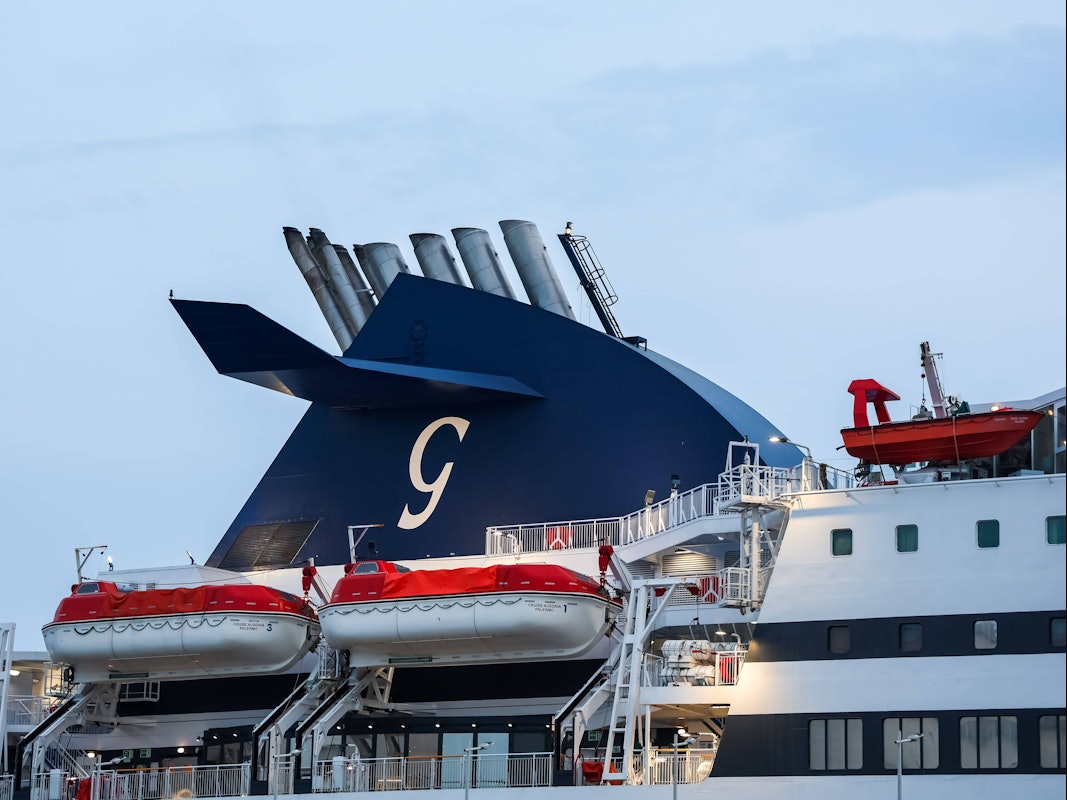 Schornstein eines Fährschiffs mit einem G-Logo und mehreren Rettungsbooten zur Sicherheit der Passagiere.