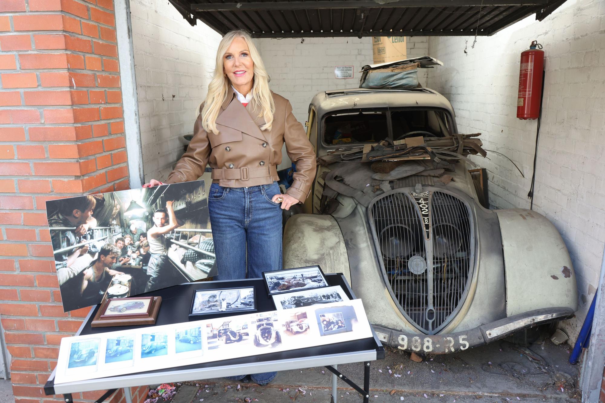 Marion Fedder, die Witwe des gestorbenen Hamburger Schauspielers Jan Fedder, steht vor einem alten Peugeot 402.