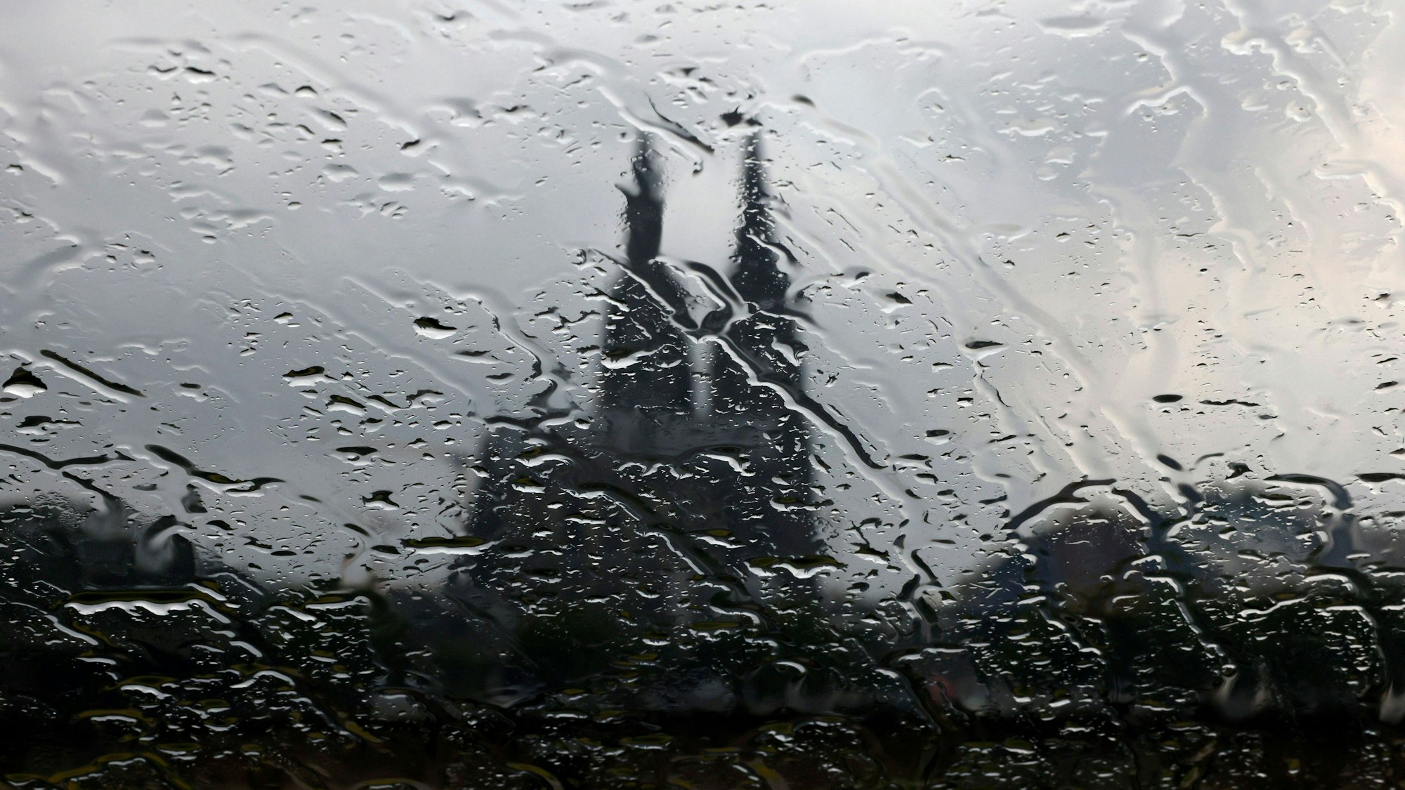 Der Kölner Dom gesehen durch eine Glasscheibe mit Regentropfen.