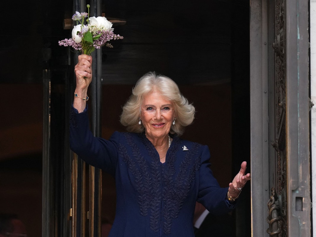 Königin Camilla winkt mit Blumen den Schaulustigen zu.