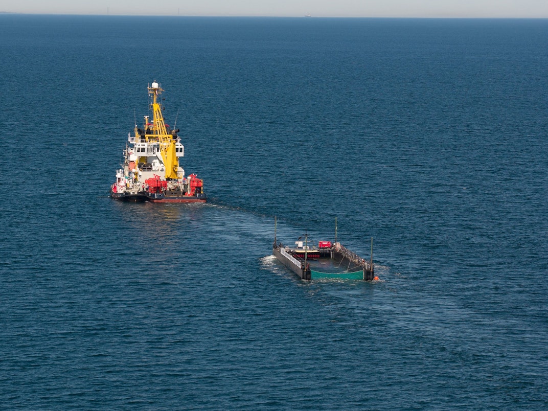Der Schlepper zieht den mit Wasser gefüllten Lastkahn mit dem Buckelwal.
