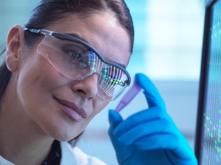 Wissenschaftlerin analysiert DNA-Proben mit Handschuhen und Brille