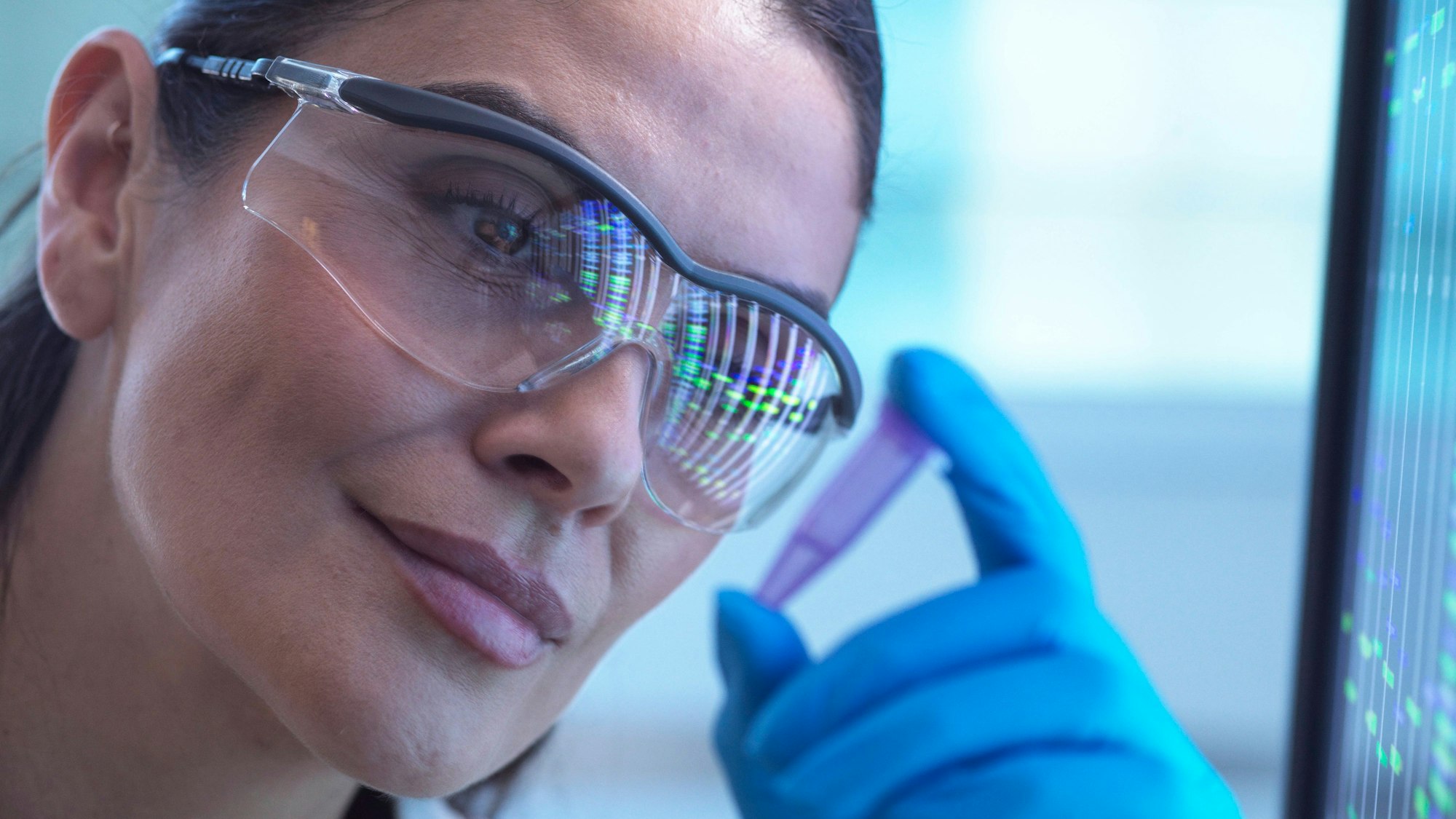 Wissenschaftlerin analysiert DNA-Proben mit Handschuhen und Brille