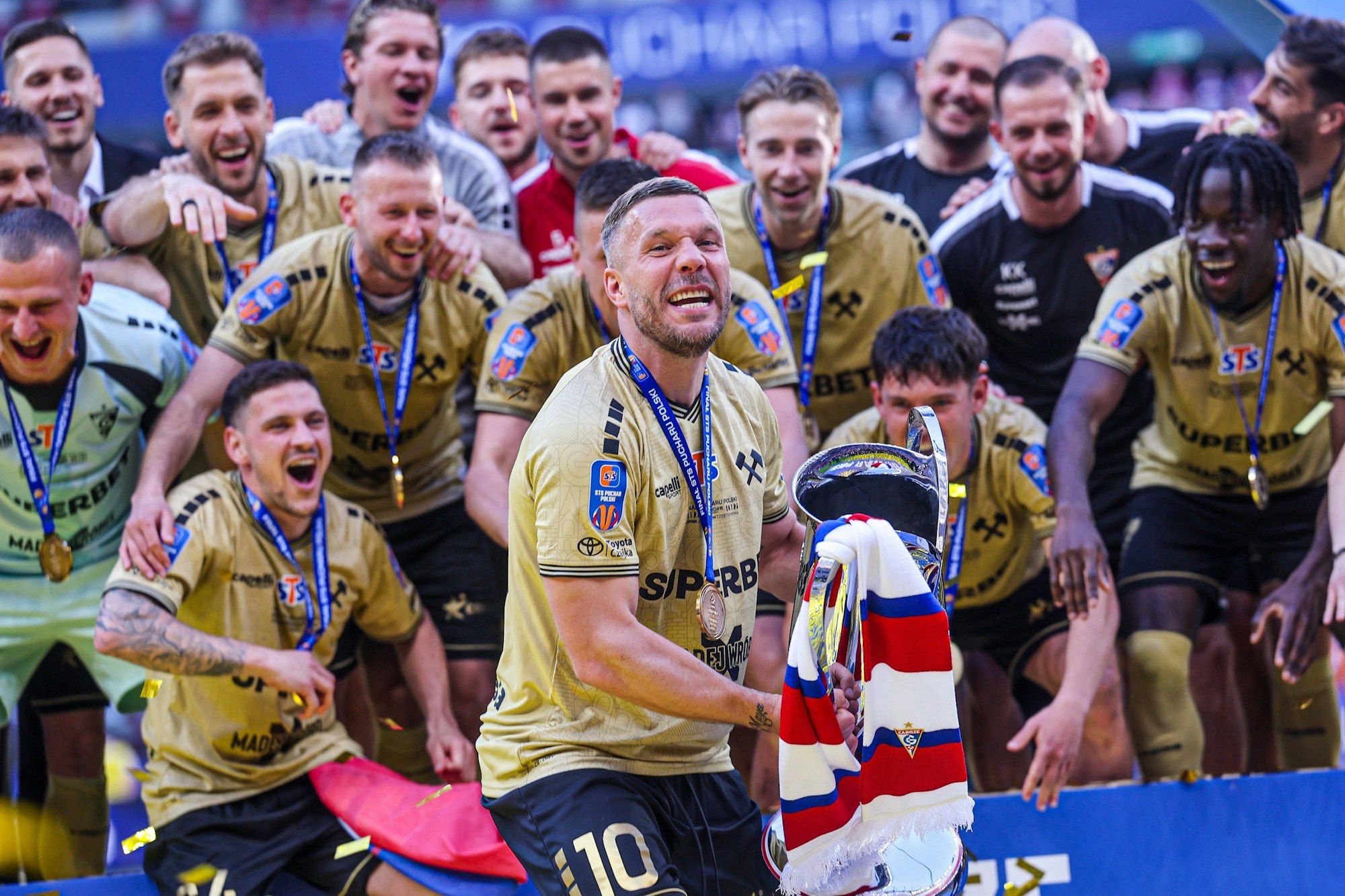 Lukas Podolski mit dem Pokal in den Händen.