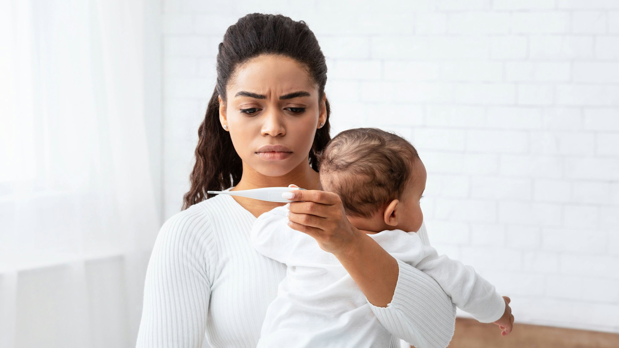 Afrikanische Mutter mit krankem Baby und Thermometer