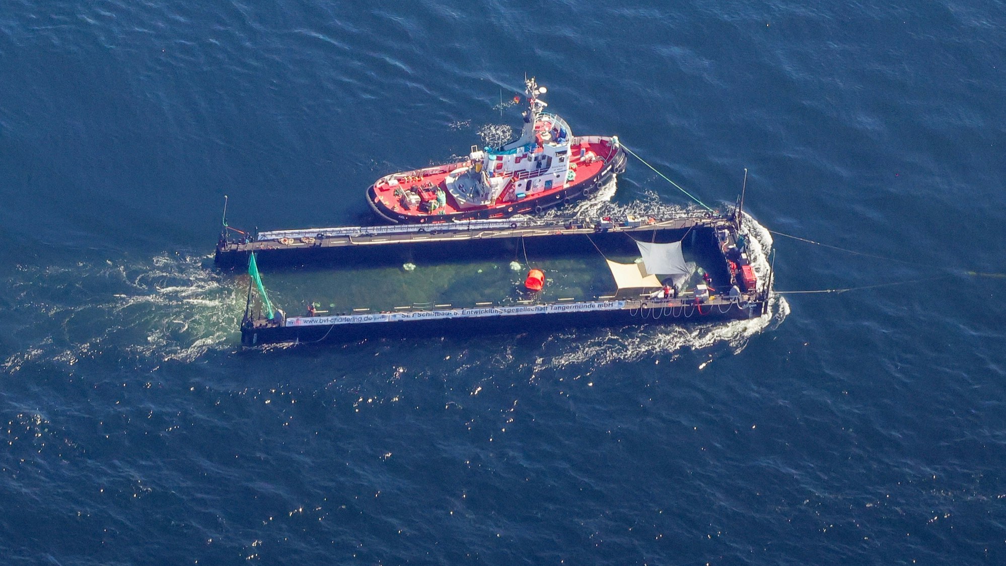 Der Buckelwal wird in seiner Barge vom Schlepper Fortuna B entlang der dänischen Küste in Höhe unterhalb von Skagen, im sogenannten Skagerrak, durch die Ostsee gezogen (Luftaufnahme aus einem Flugzeug).