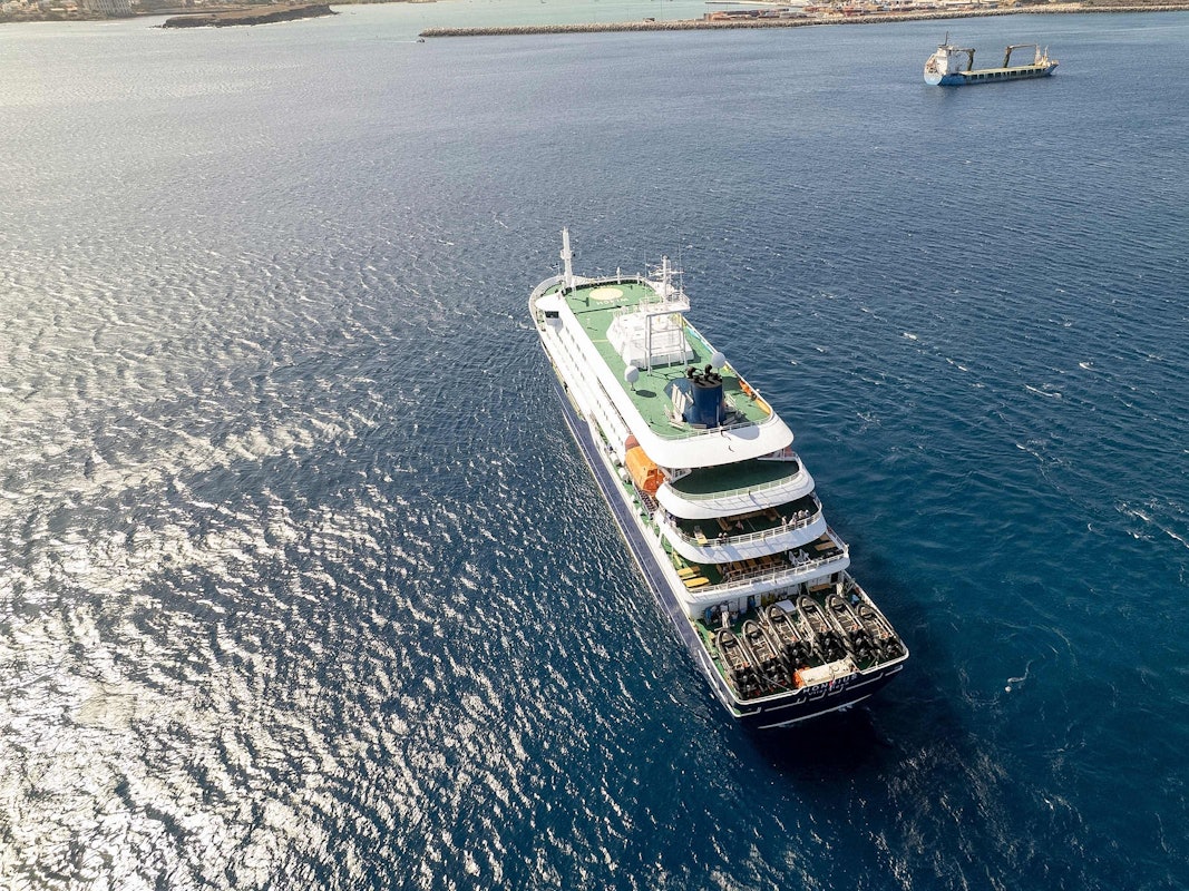 Diese Luftaufnahme zeigt das Kreuzfahrtschiff „MV Hondius“, das vor dem Hafen von Praia vor Anker liegt. Ein Ausbruch einer „schweren akuten Atemwegserkrankung“ an Bord des Schiffs hat zwei Todesopfer gefordert.