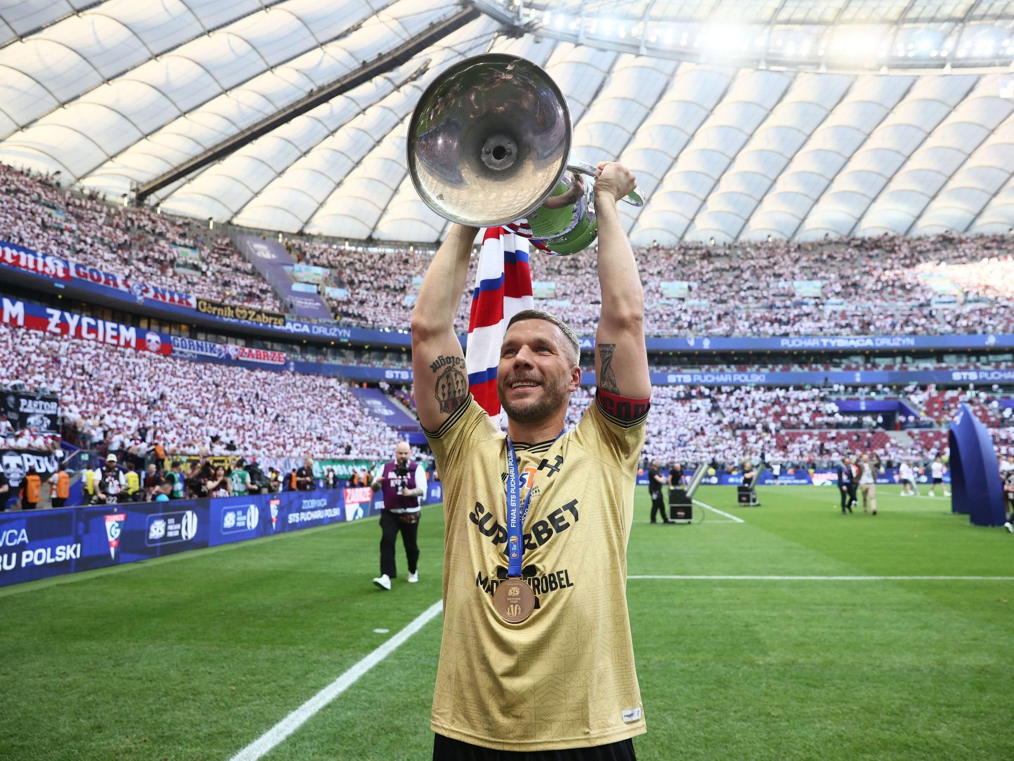Lukas Podolski hält den polnischen Pokal in die Luft.