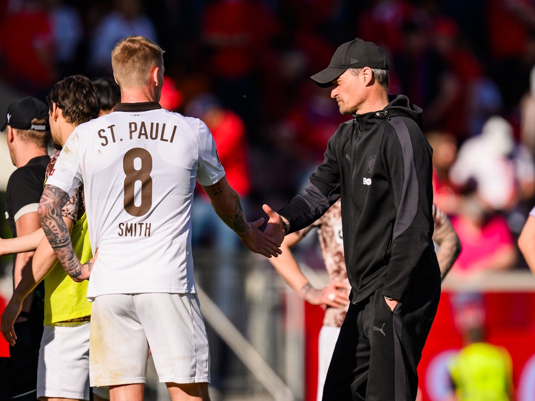 Trainer Alexander Blessin klatscht nach dem Spiel mit Eric Smith ab.