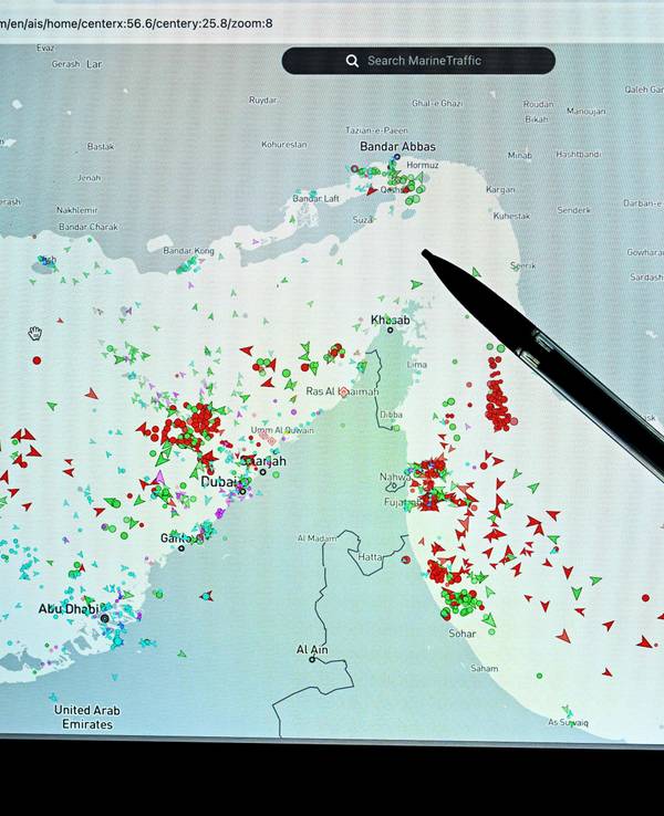 Eine Person zeigt auf eine Seite der Marinetraffic-Website, die den Schiffsverkehr am Rande der Straße von Hormuz nahe der iranischen Küste zeigt.