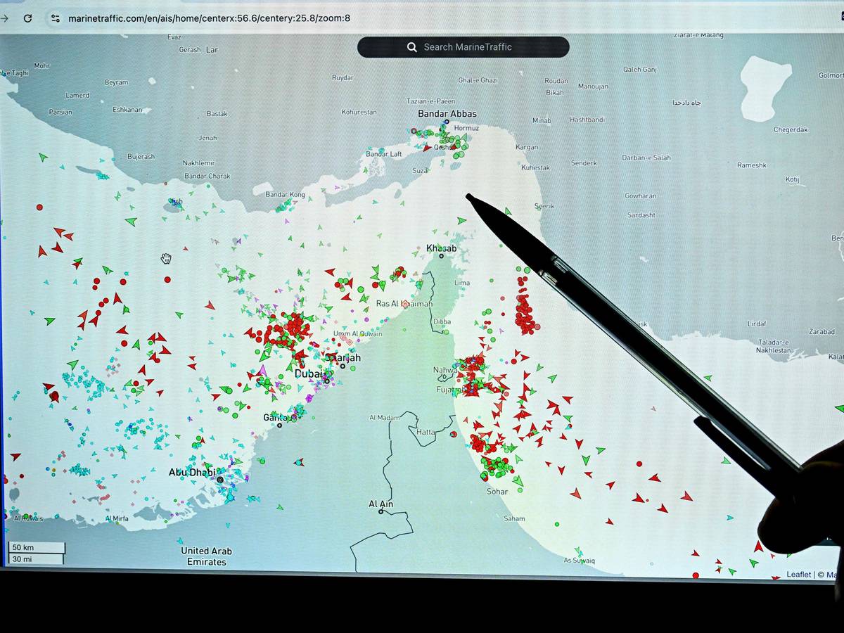 Eine Person zeigt auf eine Seite der Marinetraffic-Website, die den Schiffsverkehr am Rande der Straße von Hormuz nahe der iranischen Küste zeigt.