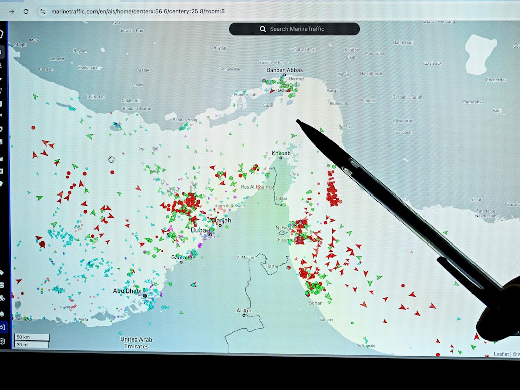 Eine Person zeigt auf eine Seite der Marinetraffic-Website, die den Schiffsverkehr am Rande der Straße von Hormuz nahe der iranischen Küste zeigt.