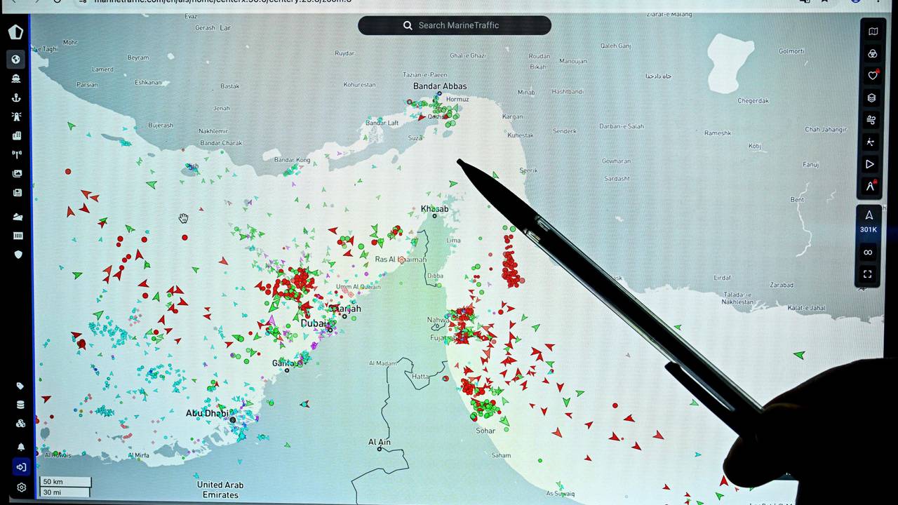 Eine Person zeigt auf eine Seite der Marinetraffic-Website, die den Schiffsverkehr am Rande der Straße von Hormuz nahe der iranischen Küste zeigt.
