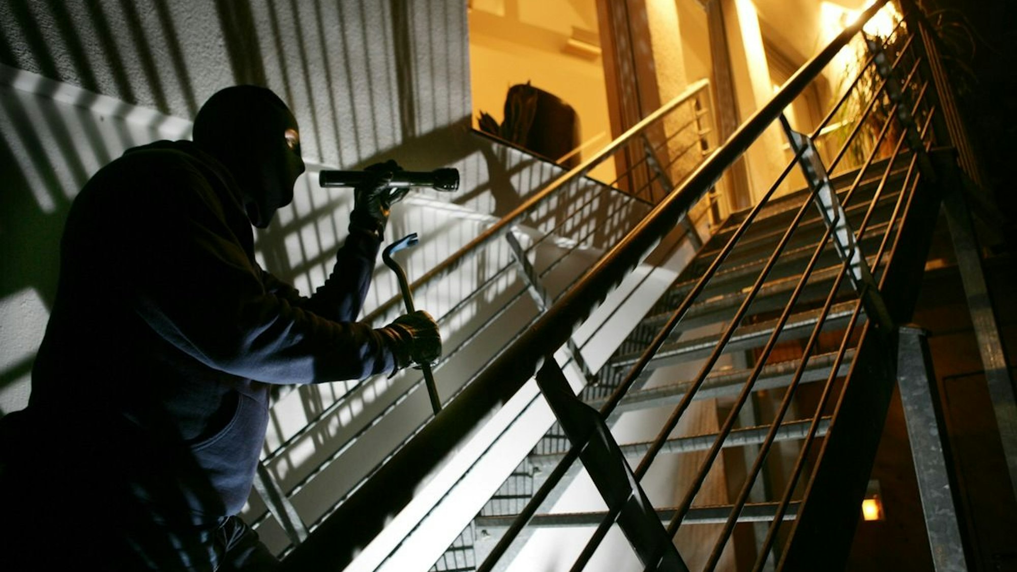 Einbrecher mit Brechstange auf einer Treppe