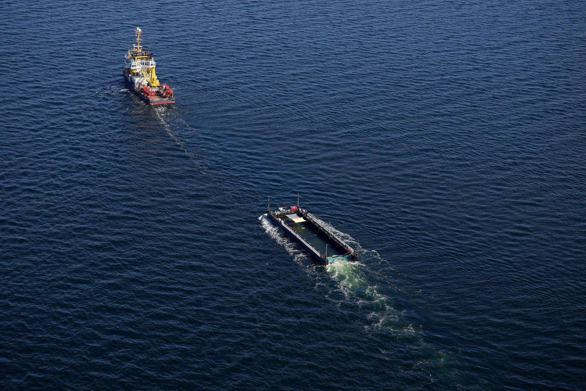 Der Buckelwal wird in seiner Barge vom Schlepper Fortuna B entlang der dänischen Küste in Höhe Aarhus in Richtung Nordsee durch die Ostsee gezogen, die Robin Hood begleitet den Konvoi weiterhin.(Luftaufnahme aus Flugzeug)