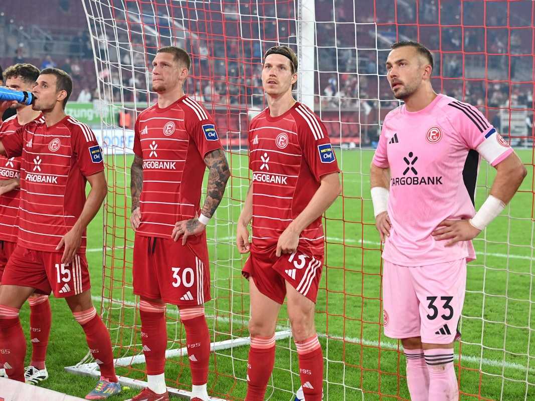 Die Spieler von Fortuna Düsseldorf stehen vor der Fankurve und sehen enttäuscht aus.