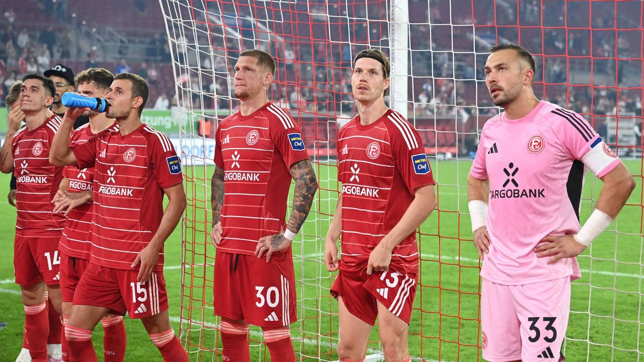 Die Spieler von Fortuna Düsseldorf stehen vor der Fankurve und sehen enttäuscht aus.