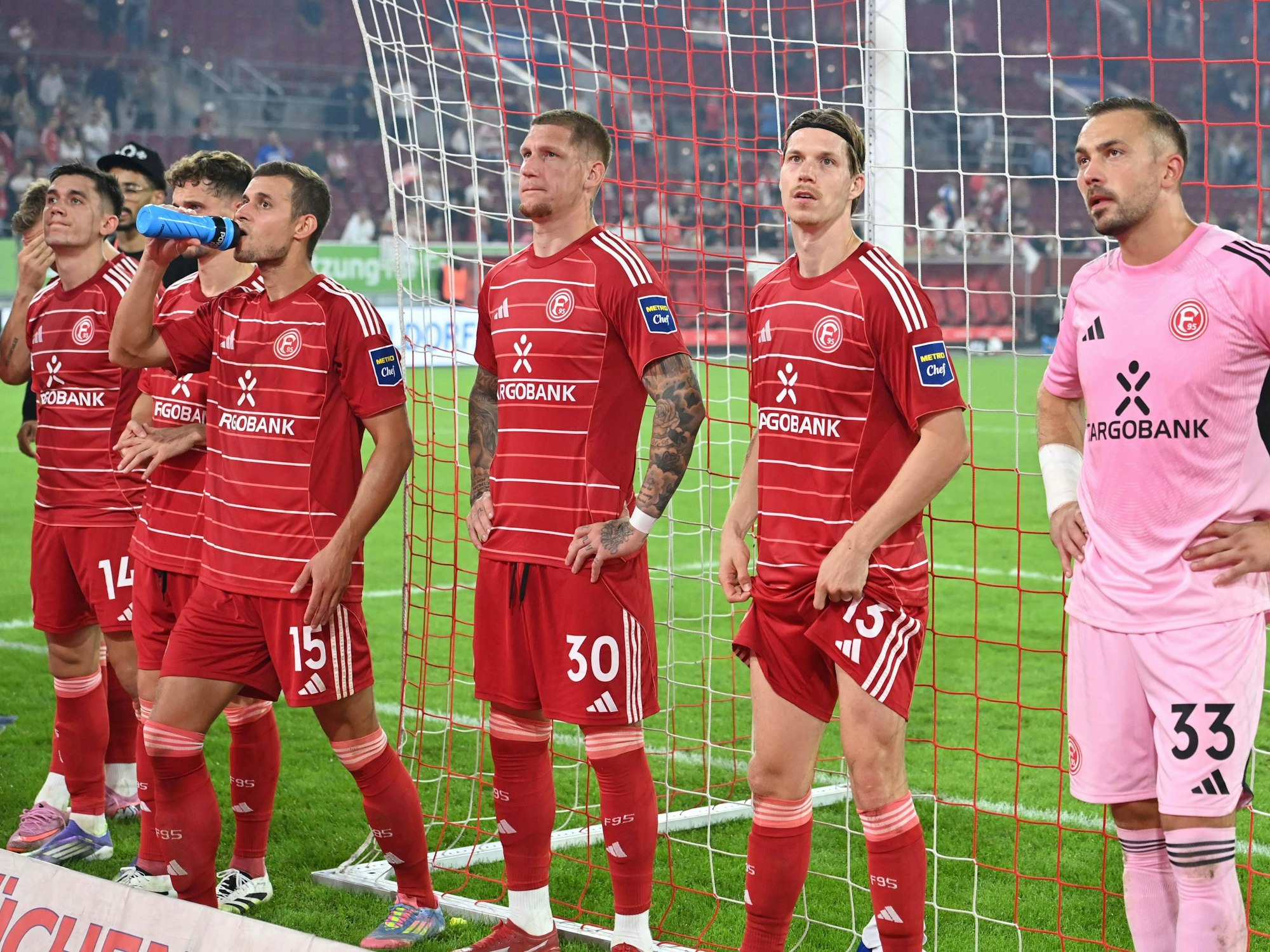 Die Spieler von Fortuna Düsseldorf stehen vor der Fankurve und sehen enttäuscht aus.