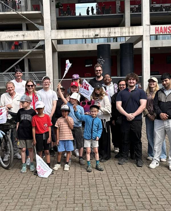 Die Paveier stehen mit Kindern vor dem Kölner Stadion.
