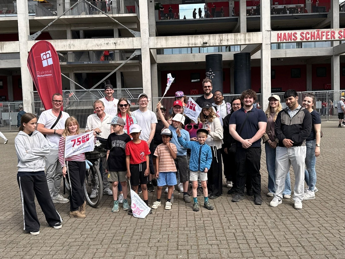 Die Paveier stehen mit Kindern vor dem Kölner Stadion.