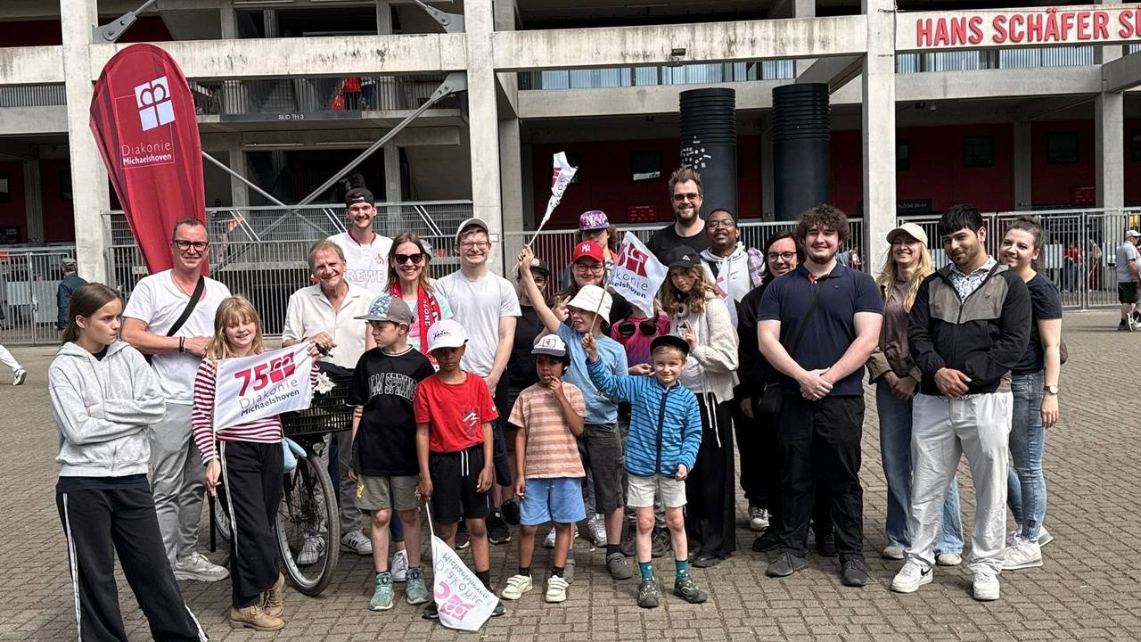 Die Paveier stehen mit Kindern vor dem Kölner Stadion.