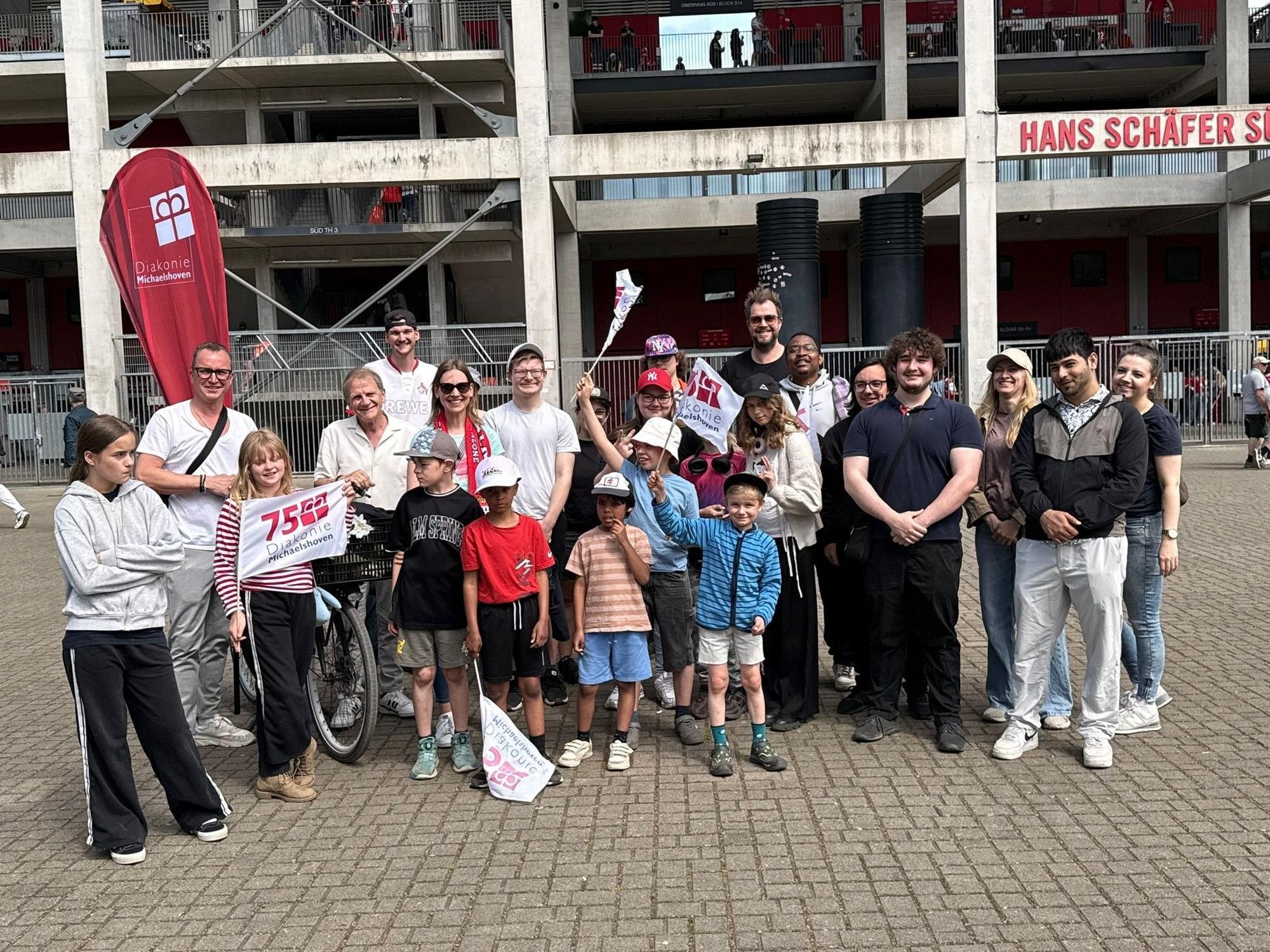 Die Paveier stehen mit Kindern vor dem Kölner Stadion.