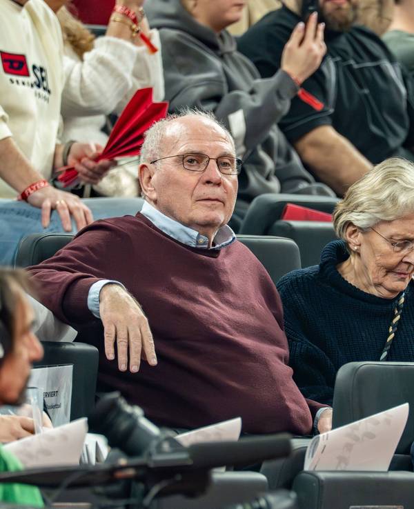 Uli Hoeneß sitzt bei einem Basketballspiel neben seiner Frau auf der Tribüne.