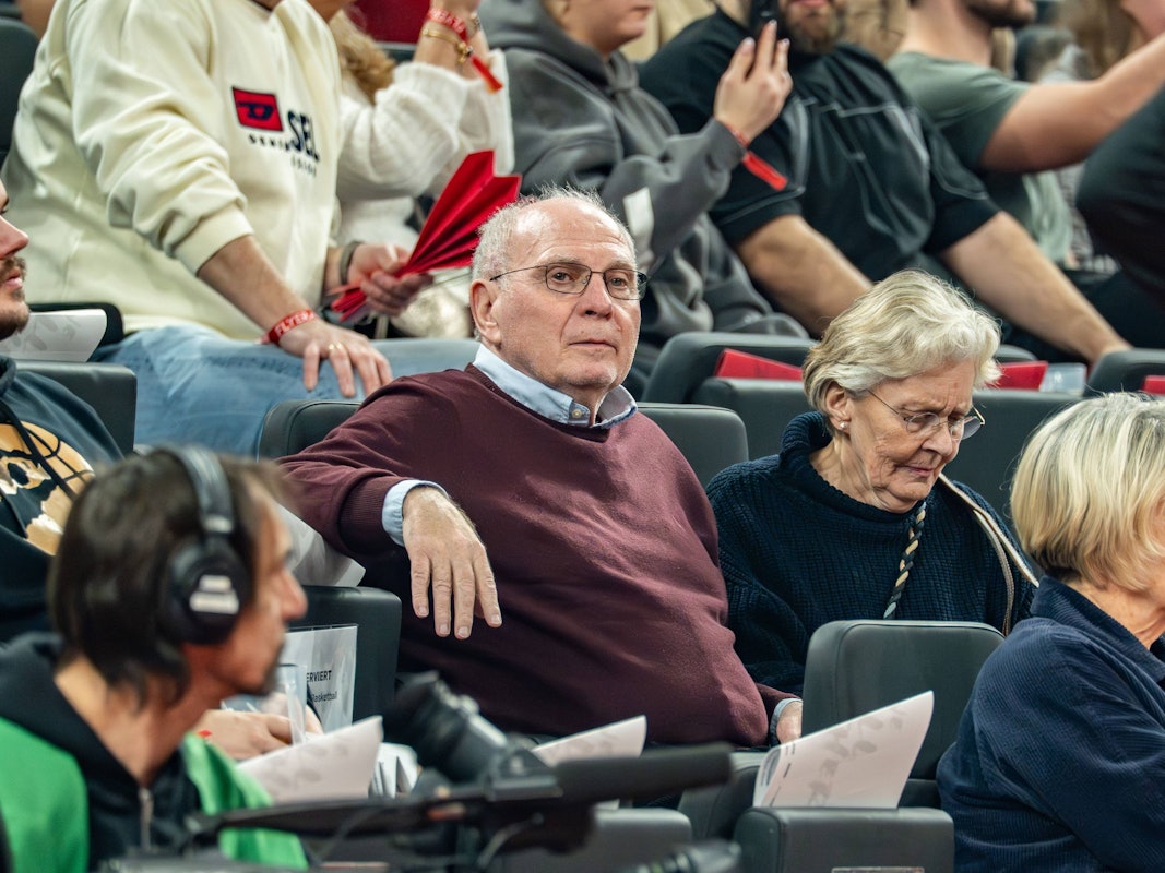 Uli Hoeneß sitzt bei einem Basketballspiel neben seiner Frau auf der Tribüne.