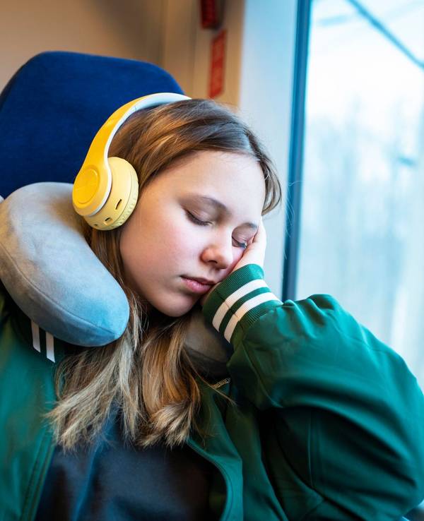 Mädchen schläft mit einem Nackenkissen im Zug