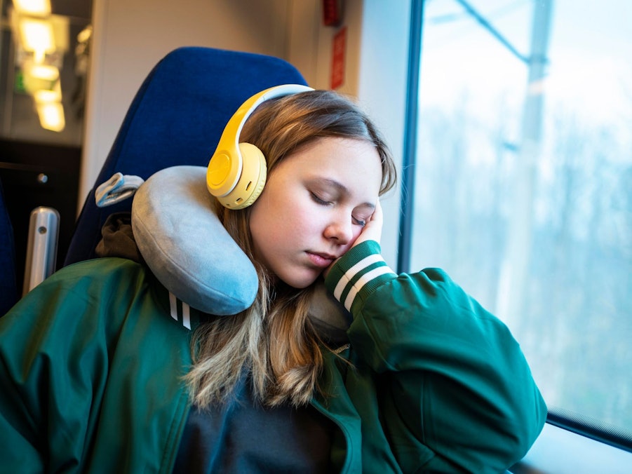 Mädchen schläft mit einem Nackenkissen im Zug